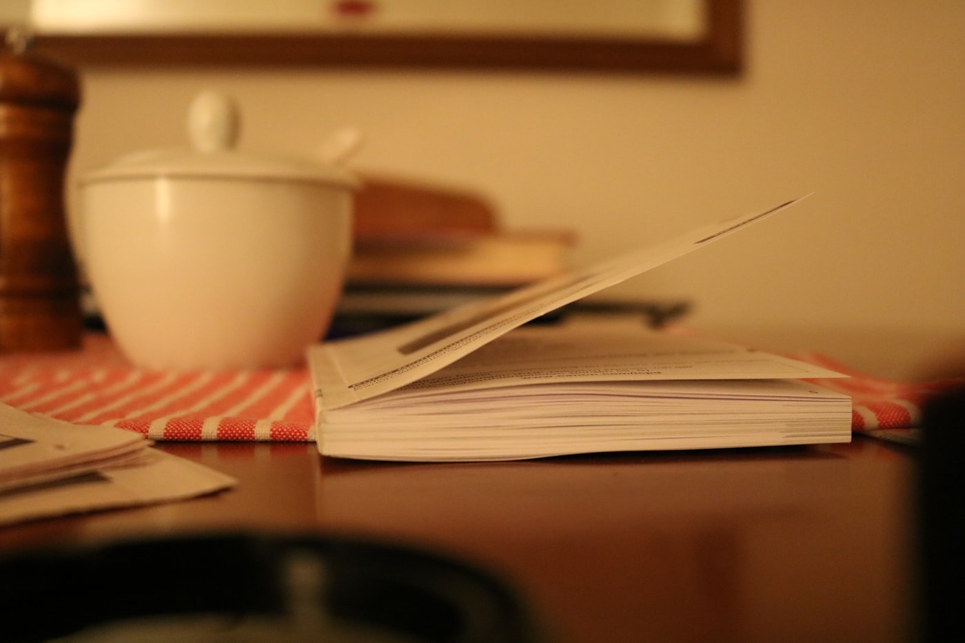 Caderno aberto sobre a mesa da cozinha, ao lado de uma tigela