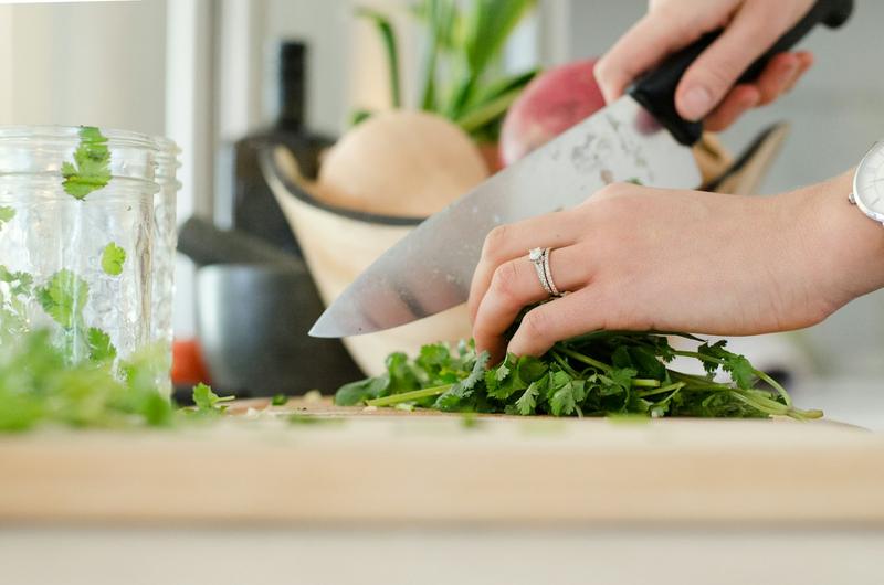 Mãos cortando legumes frescos na tábua