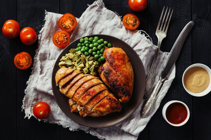 Prato com peito de frango fatiado, ervilhas e legumes